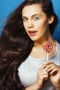 Young pretty adorable brunette woman with candy close up posing on blue background, like doll makeup, fashion beauty Royalty Free Stock Photo