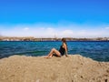 Young pretty adult girl sits on a rock and looks at the panorama of Sharm El Sheikh on the Red Sea. Caucasian woman on the Royalty Free Stock Photo