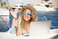 Young pretty adult woman smile and use laptop computer outdoor  lay down on the deck of a yacht - travel and summer holiday Royalty Free Stock Photo