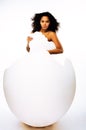 Young pretty african american woman in big cracked egg isolated on white background, fashion people concept Royalty Free Stock Photo