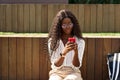 Young pretty African woman student model using mobile phone outdoors. Royalty Free Stock Photo