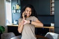 Young pretty afro woman tooking at her wrist watch while sitting on a table in a kitchen Royalty Free Stock Photo