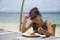 Young pretty anf happy Asian Chinese woman having lunch at resort beach restaurant in front of the sea eating healthy food Royalty Free Stock Photo