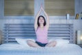 Young pretty Asian Chinese woman 20s or 30s relaxing at home bedroom sitting on bed in lotus yoga position in meditation and relax Royalty Free Stock Photo