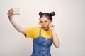 Young pretty Asian girl who wearing a jeans dungaree and yellow glasses, taking selfie, smiling