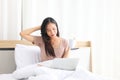 Young pretty Asian girl working from home on her bed using computer laptop to access her work online Royalty Free Stock Photo