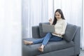 Young pretty Asian woman sitting on sofa. Young Asian woman working with a laptop computer sitting on the cozy sofa Royalty Free Stock Photo