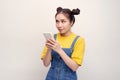 Young pretty Asian woman wearing a jeans dungaree and holding smartphone Royalty Free Stock Photo