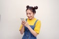 Young pretty Asian woman wearing a jeans dungaree and holding smartphone