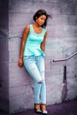 Portrait of Young Lonly Woman Standing outdoors against wall, looking down, sad, thinking Royalty Free Stock Photo