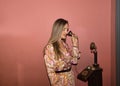 Young, pretty, blonde woman in flower dress, talking on antique candelabra phone on magenta background. Concept antiques,