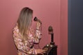 Young, pretty, blonde woman in a flowered dress dialing on the dial of an antique candlestick telephone on a magenta background. Royalty Free Stock Photo