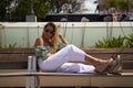 Young, pretty blonde woman sitting on a park bench. The woman is happy and smiling Royalty Free Stock Photo