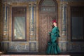 Young, pretty, blonde woman in typical green colored flamenco suit, posing with beautiful tiled wall in background. Flamenco