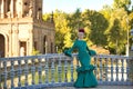 Young, pretty, blonde woman in typical green colored flamenco suit, posing leaning on a tiled railing over a bridge. Flamenco Royalty Free Stock Photo