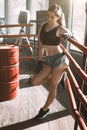 Young pretty boxer woman standing on ring. Full body portrait of boxer woman wearing black sports bra, grey trousers Royalty Free Stock Photo