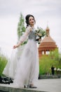 Young and pretty bridesmaid with bridal bouquet holding her elegant dress before the wedding ceremony Royalty Free Stock Photo