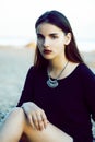 Young pretty brunette girl with long hair waiting alone on sand at seacoast, lifestyle people concept Royalty Free Stock Photo