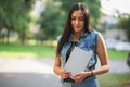 Young pretty brunette girl with the tablet and listening to music on the street. Close up.