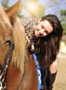Young pretty brunette riding and caressing her horse outdoor Royalty Free Stock Photo