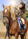 Young pretty brunette riding and caressing her horse outdoor Royalty Free Stock Photo