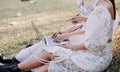 Young pretty brunette twin girls sitting on the grass with legs slightly bent in knees and looking in a brown book, wearing casual Royalty Free Stock Photo