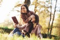 Young pretty brunette twin girls sitting on the grass. One of them is trying to read a brown books, while onother one is Royalty Free Stock Photo