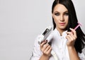 Young pretty brunette woman dermatologist in white clothing standing and holding equipment for laser hair removal and
