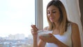 Woman Eating Cereal With Milk Out Of Bowl Standing At Window And Looking Outside Royalty Free Stock Photo