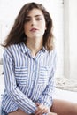 Young pretty brunette woman in her bedroom sitting at window, happy smiling lifestyle people concept Royalty Free Stock Photo