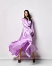 Young pretty brunette woman in purple silk maxi dress and shoes standing feeling light and soft after laser hair removal Royalty Free Stock Photo