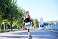 Young pretty brunette woman, riding roller blades in city park in the morning. Fit sporty girl, wearing black top and white shorts Royalty Free Stock Photo