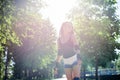 Young pretty brunette woman, riding rollerblades in city park with green trees in glimmer light. Fit sporty girl, wearing black