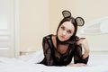 Young pretty brunette woman wearing lace mouse ears, laying waiting dreaming in bed Royalty Free Stock Photo