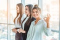 Young pretty business girls show a good gesture. Dressed in classic clothes, Royalty Free Stock Photo