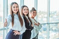 Young pretty business girls show a good gesture. Dressed in classic clothes, Royalty Free Stock Photo