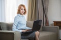 Young pretty business woman with laptop sitting on couch in the hotel room Royalty Free Stock Photo