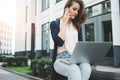 Young pretty business woman sits in business district and discussing about work on smartphone and search information in internet