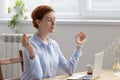 Young pretty businesswoman meditating, doing breathing exercises in office