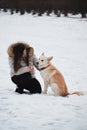 Spend holidays with dog in nature. Young pretty Caucasian girl with long hair is sitting in winter park with her friend white