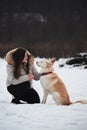 Spend holidays with dog in nature. Young pretty Caucasian girl with long hair is sitting in winter park with her friend white