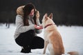Spend holidays with dog in nature. Young pretty Caucasian girl with long hair is sitting in winter park with her friend white