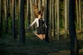 Young pretty caucasian teen girl with long flowing hair in casual clothes jumping high in the dark forest in the evening