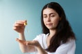 A young pretty Caucasian woman with dark hair drips a cosmetic product into the palm of her hand with a pipette. Blue