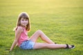 Young pretty child girl laying down on green grass lawn on warm summer day Royalty Free Stock Photo