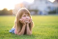 Young pretty child girl laying down on green grass lawn on warm summer day Royalty Free Stock Photo