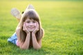 Young pretty child girl laying down on green grass lawn on warm summer day Royalty Free Stock Photo