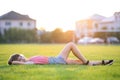 Young pretty child girl laying down on green grass lawn on warm summer day Royalty Free Stock Photo