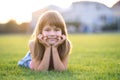 Young pretty child girl laying down on green grass lawn on warm summer day Royalty Free Stock Photo