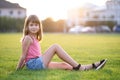 Young pretty child girl laying down on green grass lawn on warm summer day Royalty Free Stock Photo